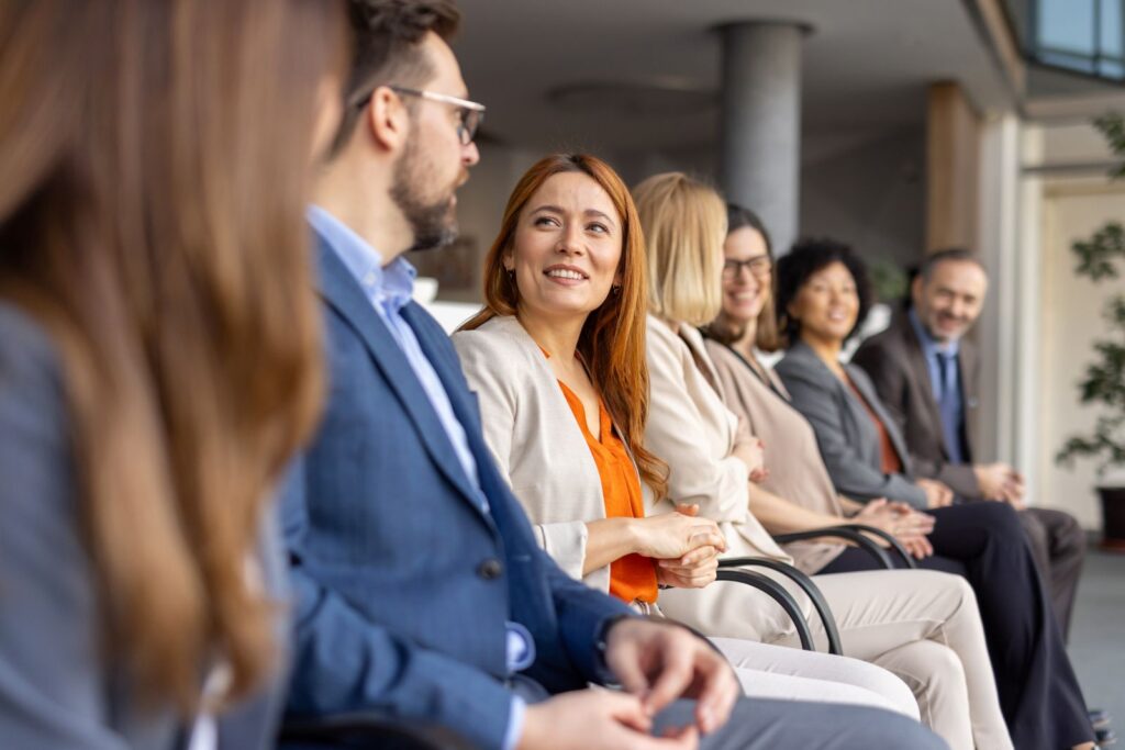 People sitting in a row of chairs smiling and talking amongst themselves.