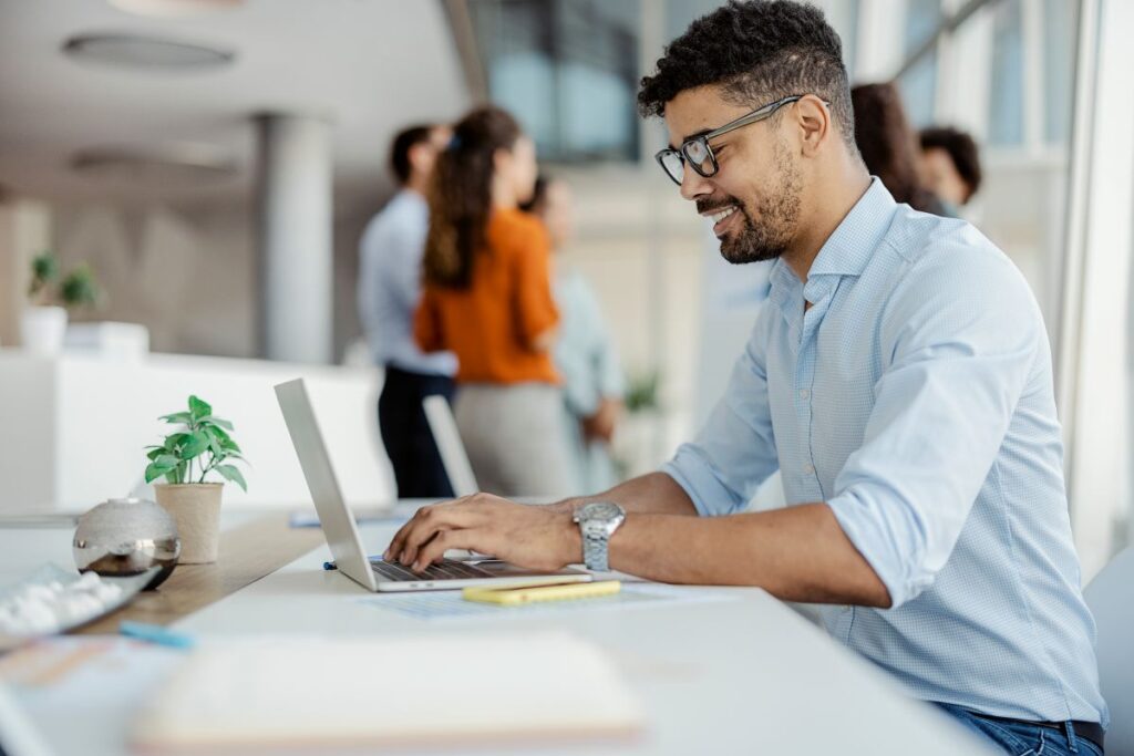 Person typing on laptop positioned on a work bench in office setting.